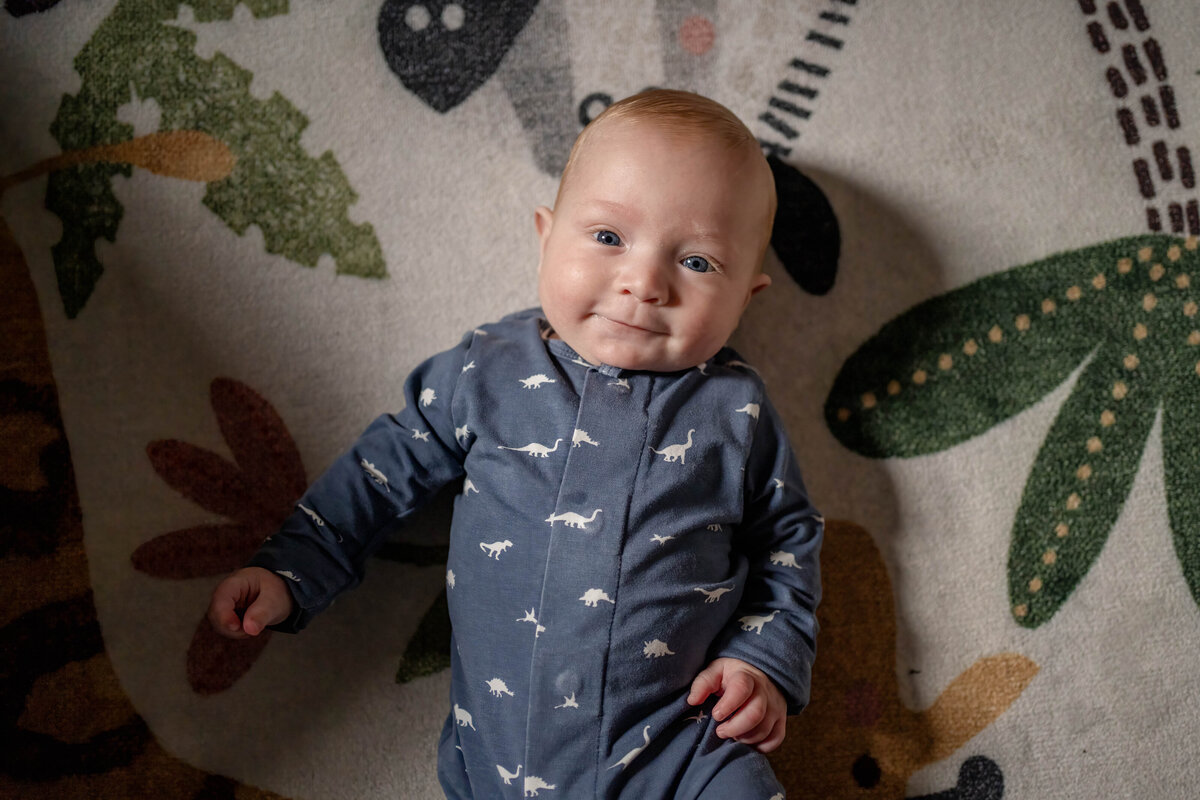 Baby boy laying on jungle themed rug in nursery