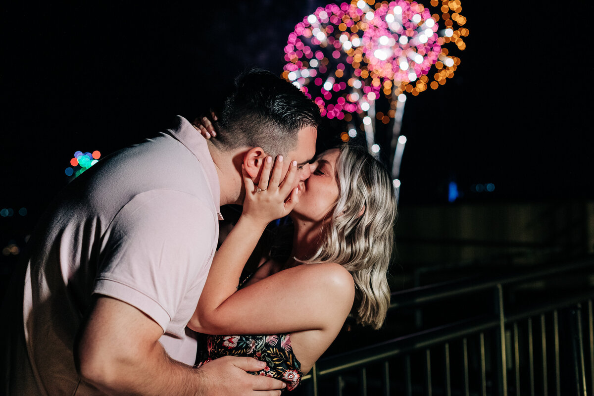 Couple kissing with fireworks in the background during surprise proposal at Disney's California grill