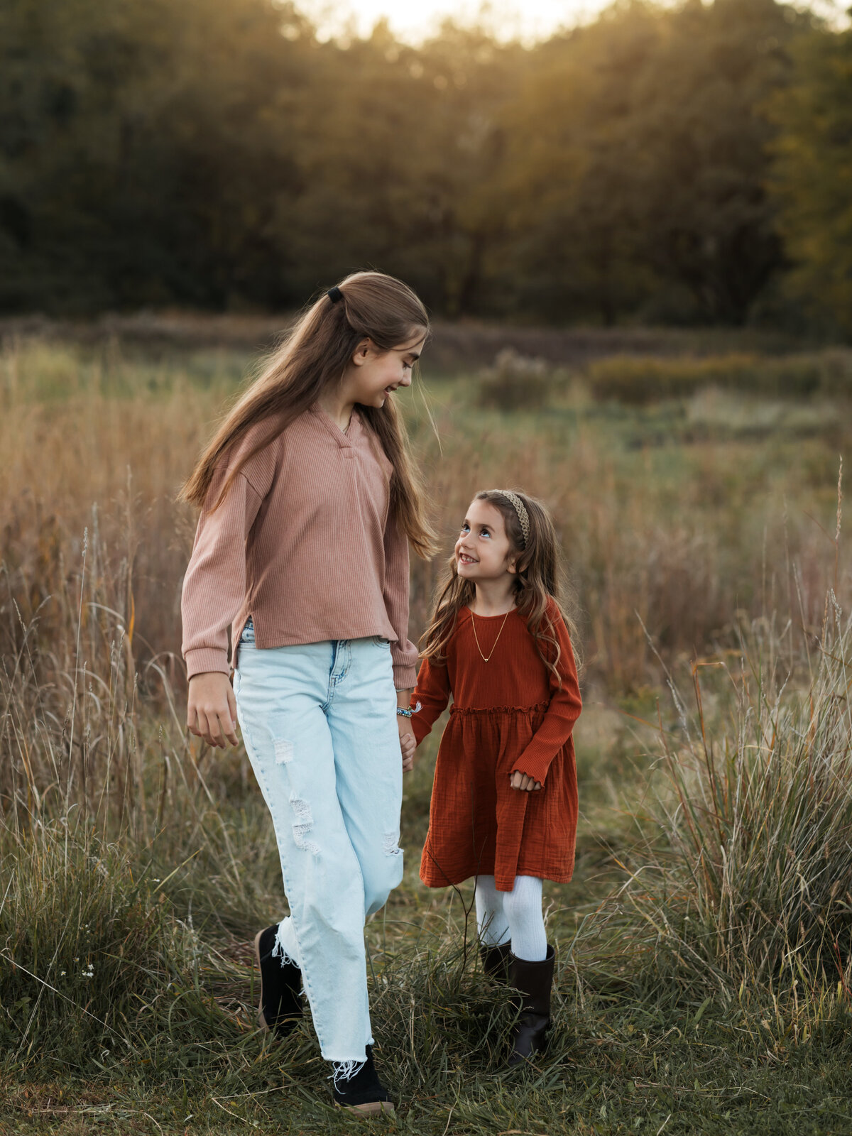 two sisters walking in field for family photoshoot
