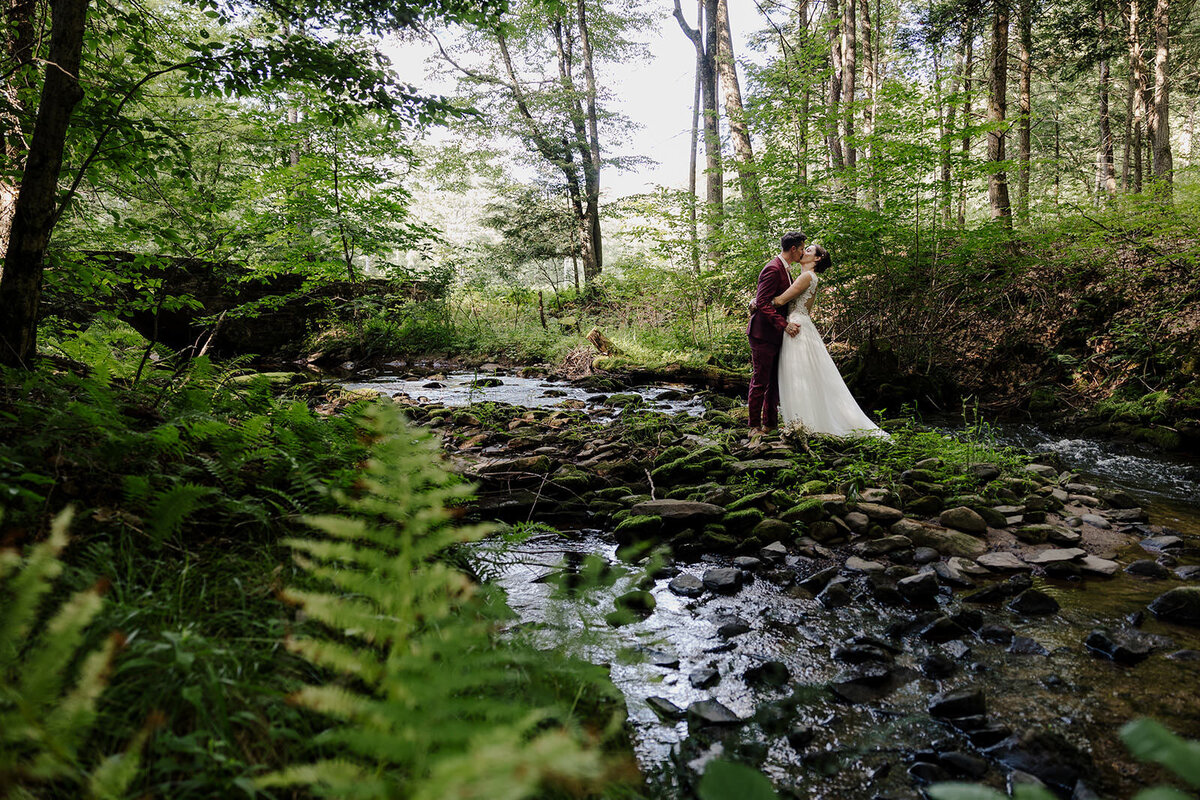 Newlyweds kissing next to a small river