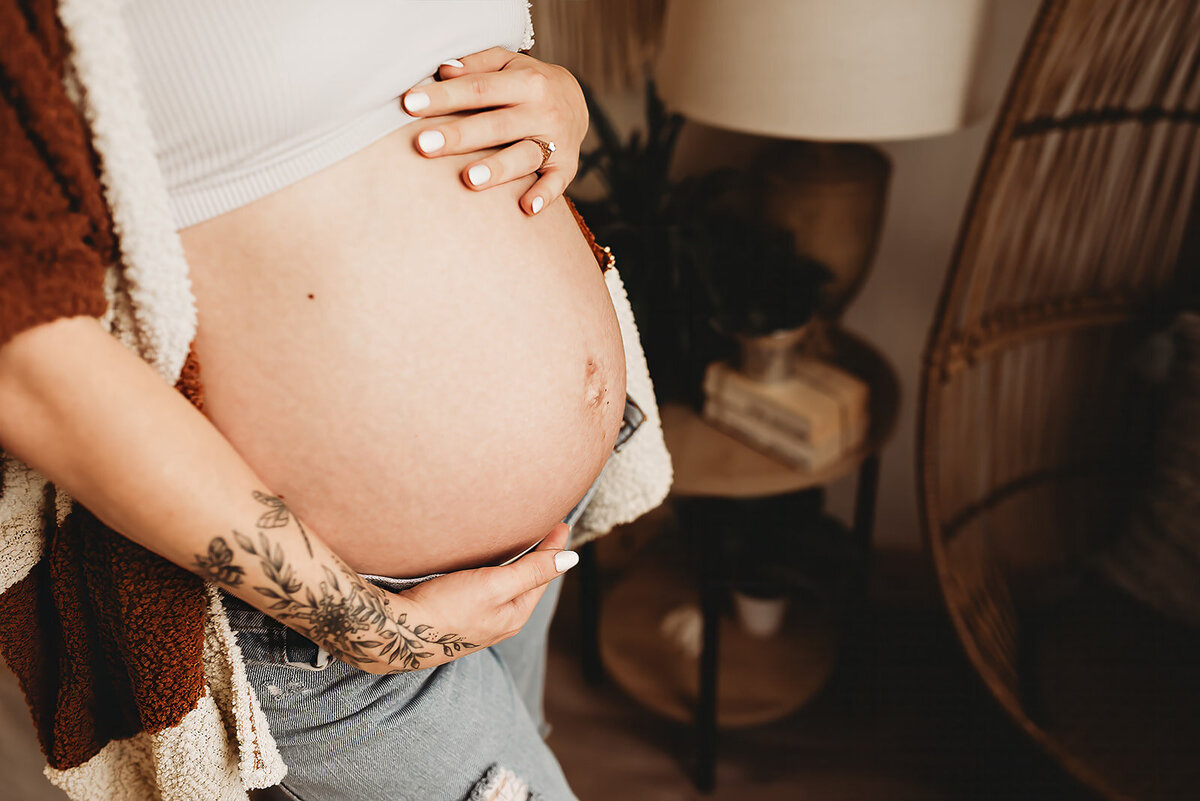 Detailed closeup of a momma embracing her growing baby bump at Nikii Pix Studios