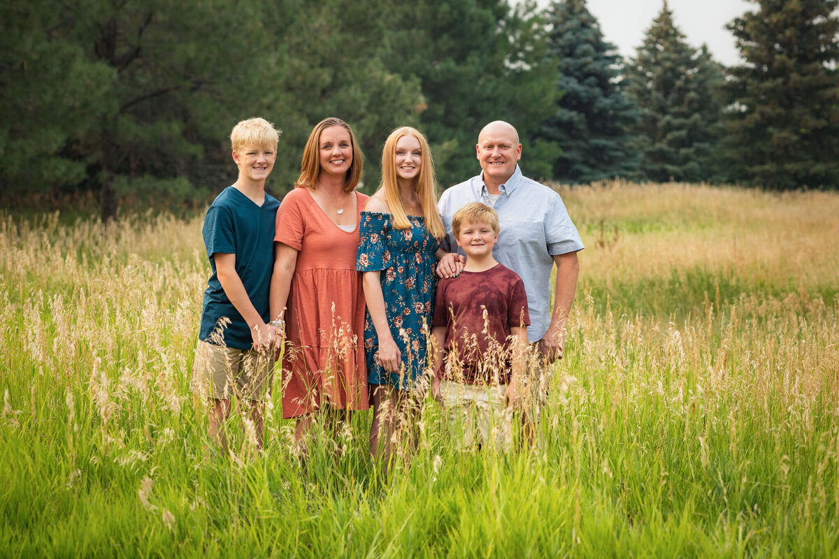 family of five standing together in a field in Colorado Springs
