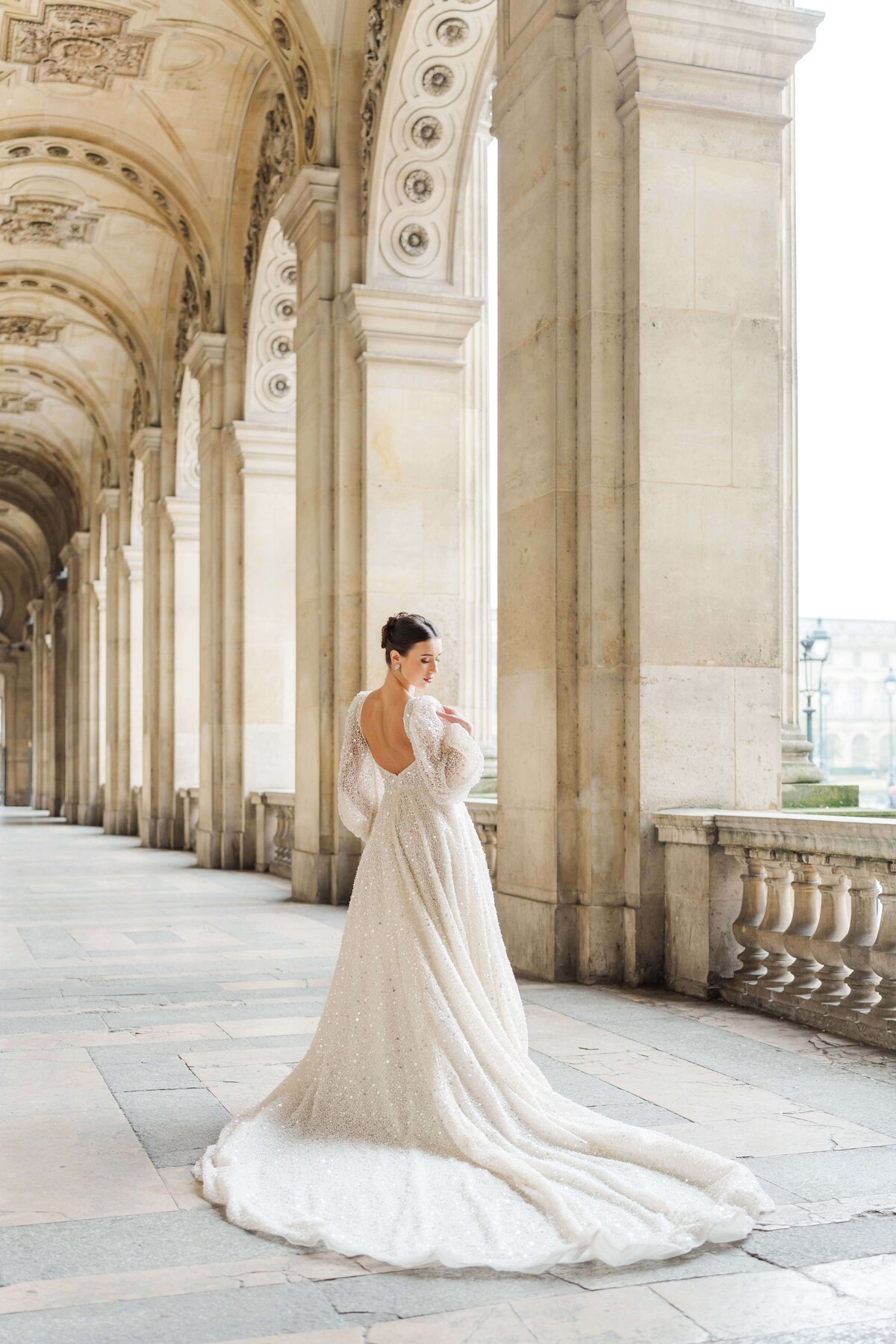 bride on her wedding dress standing, open back, om the louvre museum in paris