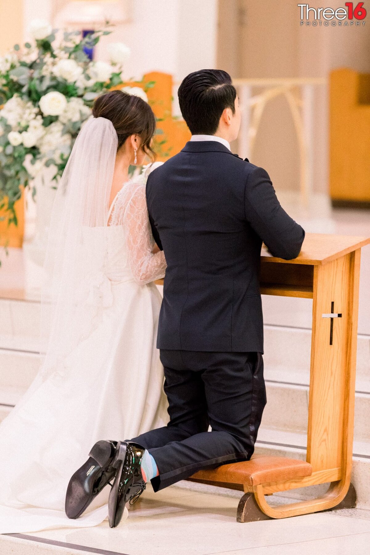 Bride and Groom kneel at the altar during a traditional Catholic church wedding