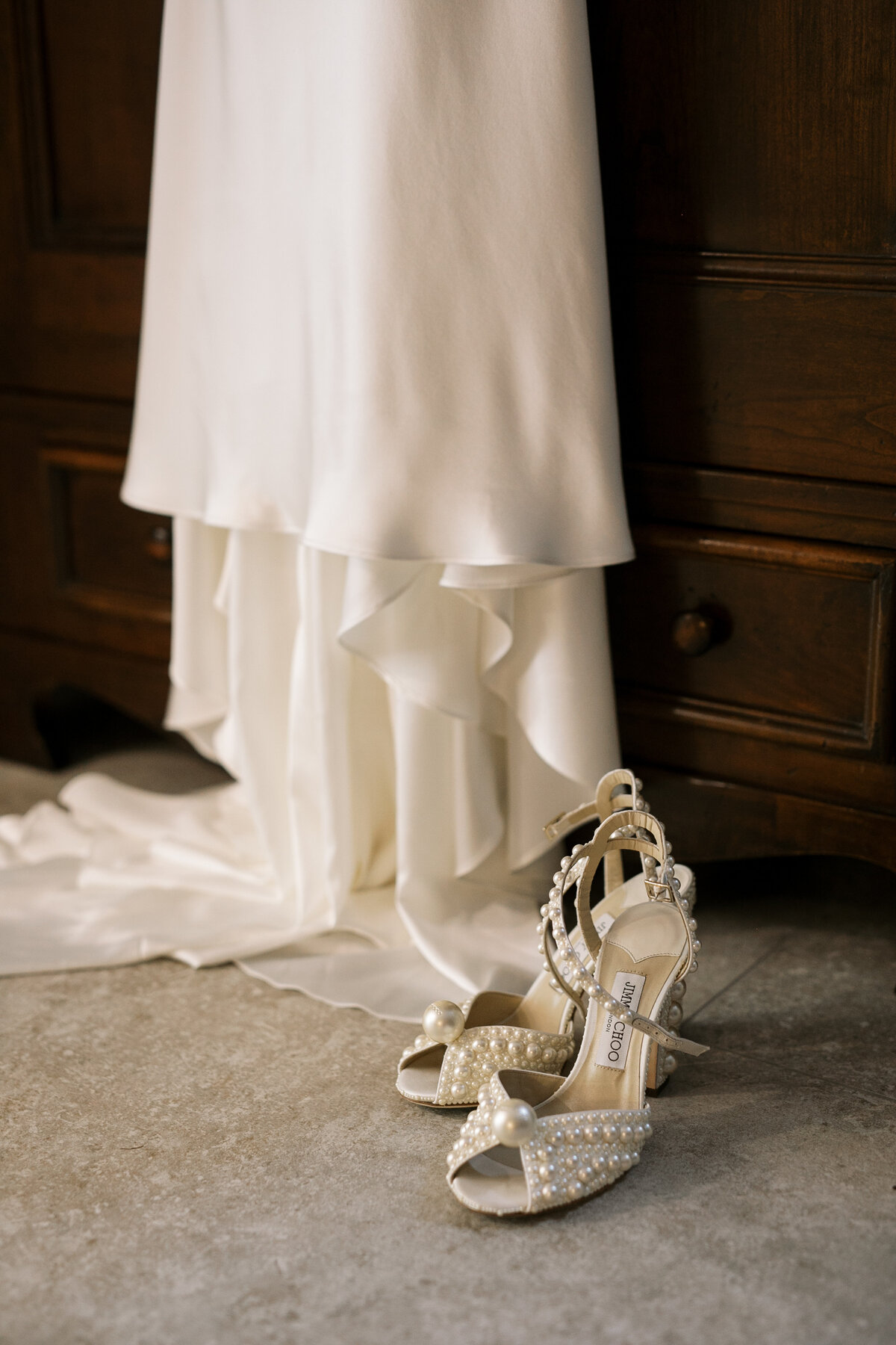 Detail of a satin wedding gown, next to pearl Jimmy Choo heels