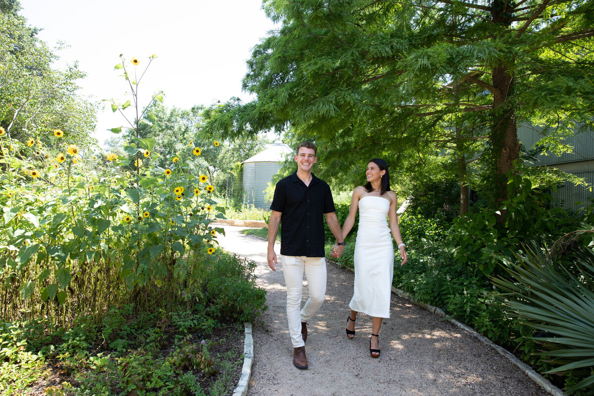 An Austin wedding photographer capturing a couple as they walk down a path in a garden.