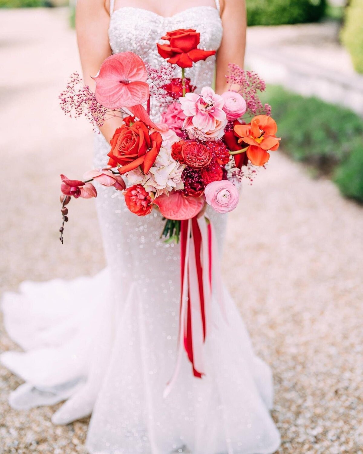 Bride holding bright red, pink, coral, and white wedding bouquet