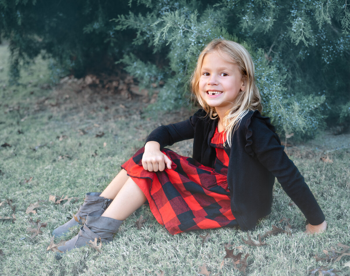 McKinney, TX little girl posing by cedar trees on a cool foggy morning during the outdoor family  photo session.