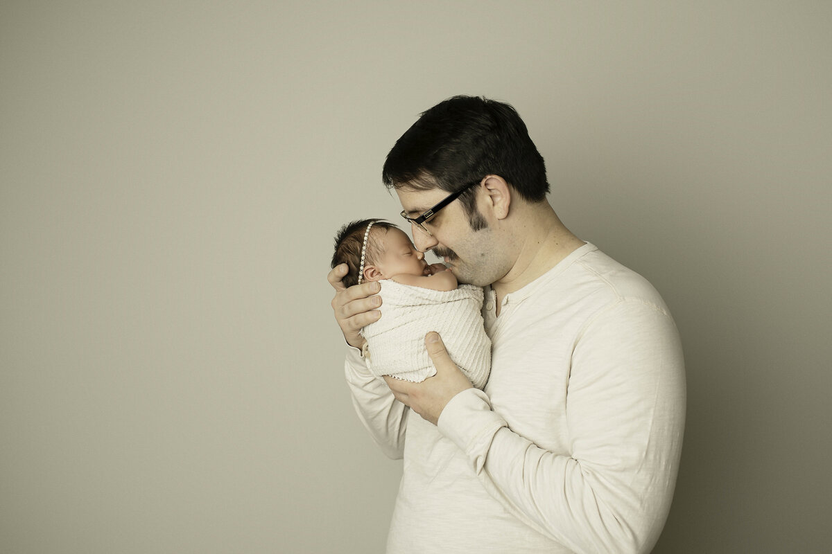 Dad gently cradles his newborn, touching noses in a tender and heartfelt moment, capturing the deep bond between father and baby