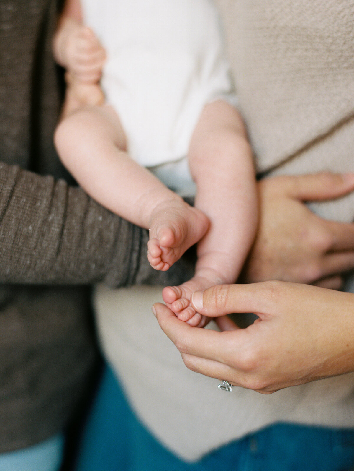 Close up image of a baby's small feet and parents' hands