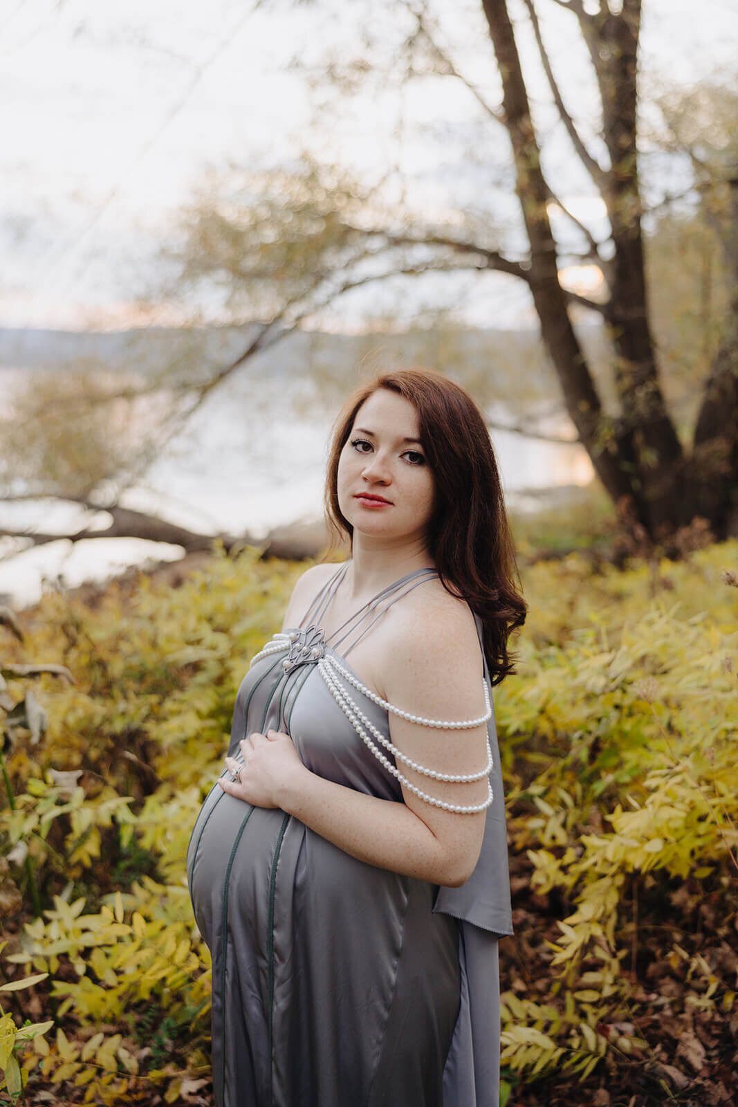 Woman wearing silk dress in woodland for maternity photo session in Fingerlakes, NY