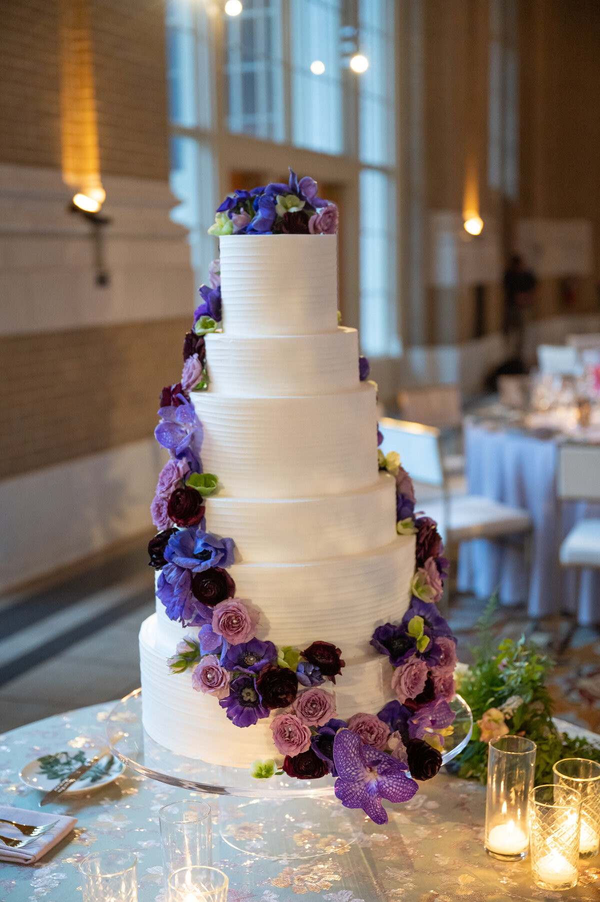 Six tier white wedding cake with fresh flowers and orchids