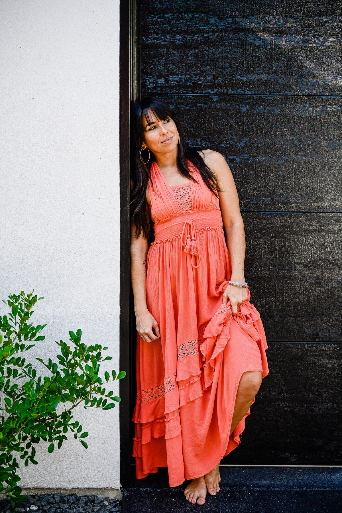 photography branding with business owner wearing a coral dress leaning against a dark wooden door