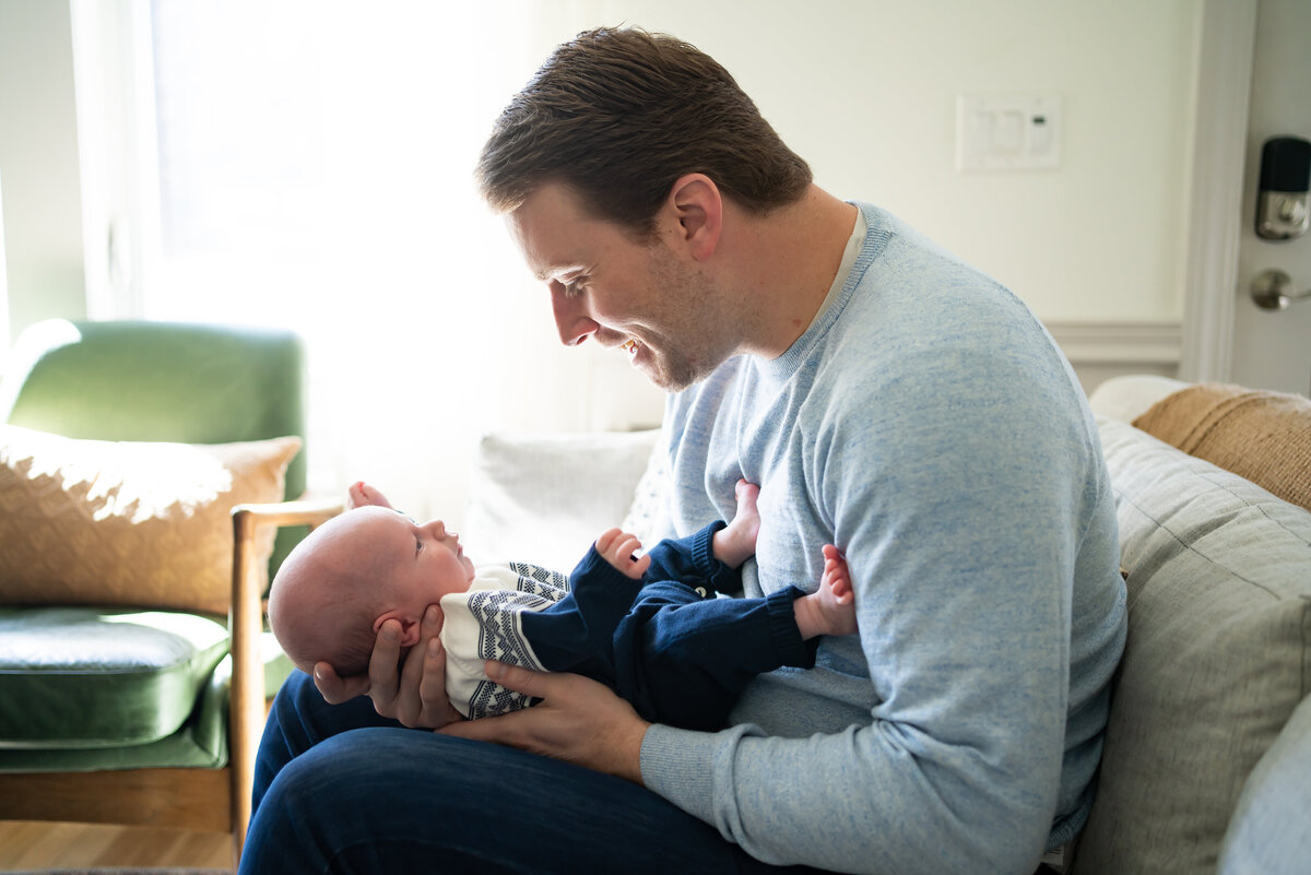 Dad holding baby in lap looking at him and smiling