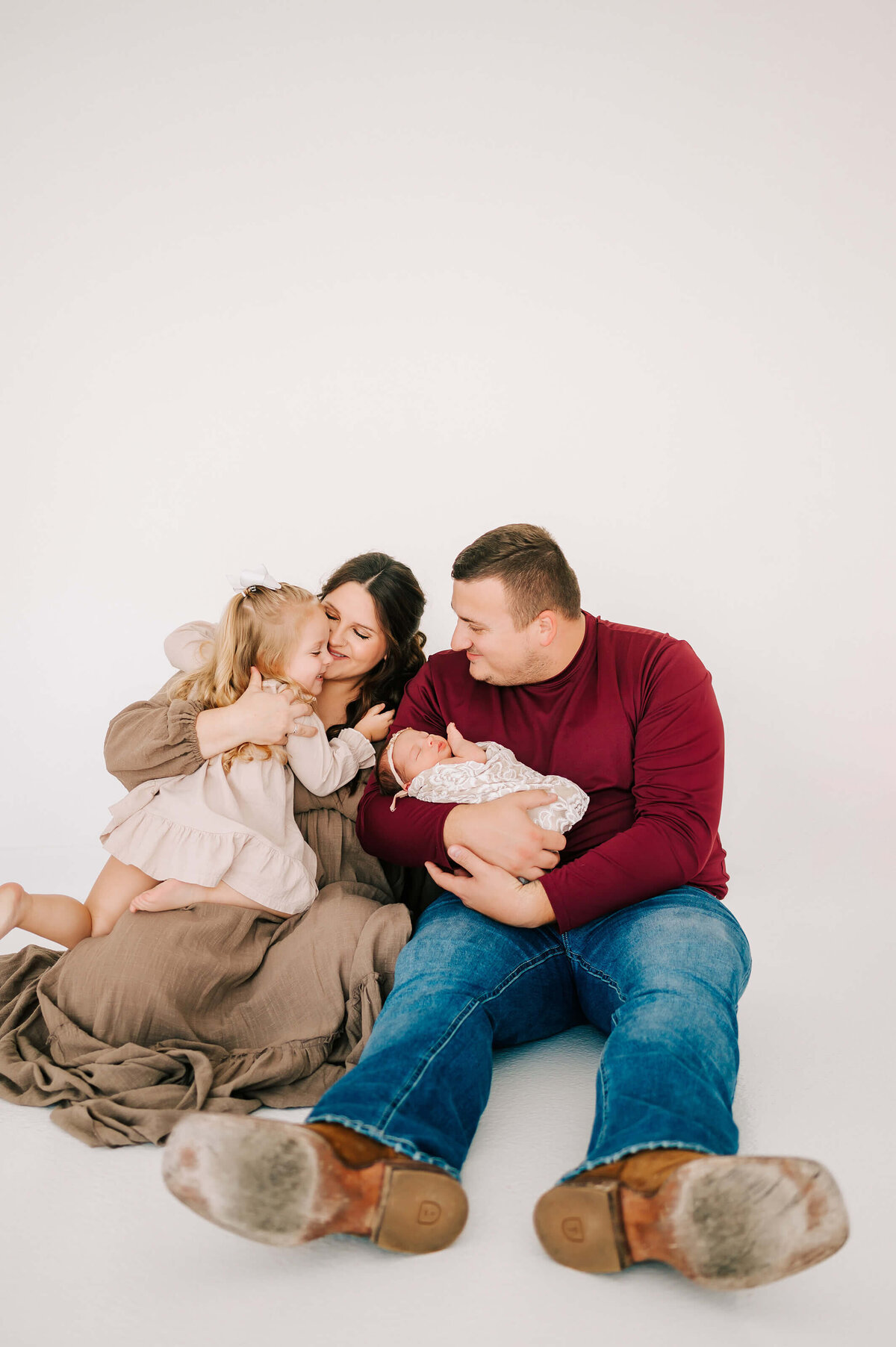 family of 4 hugging while sitting on floor during Springfield Mo newborn photogrpahy session
