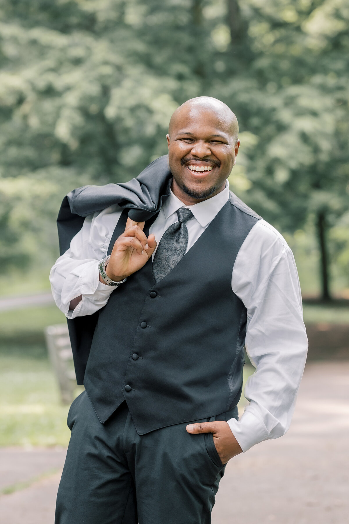 Black Groom posing with his suit jacket hanging off his shoulder during his elopement at Saratoga State Park.