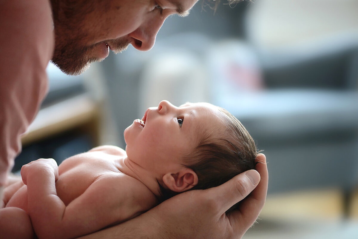 A father holding his daughter in his hands while gazing into her eyes.