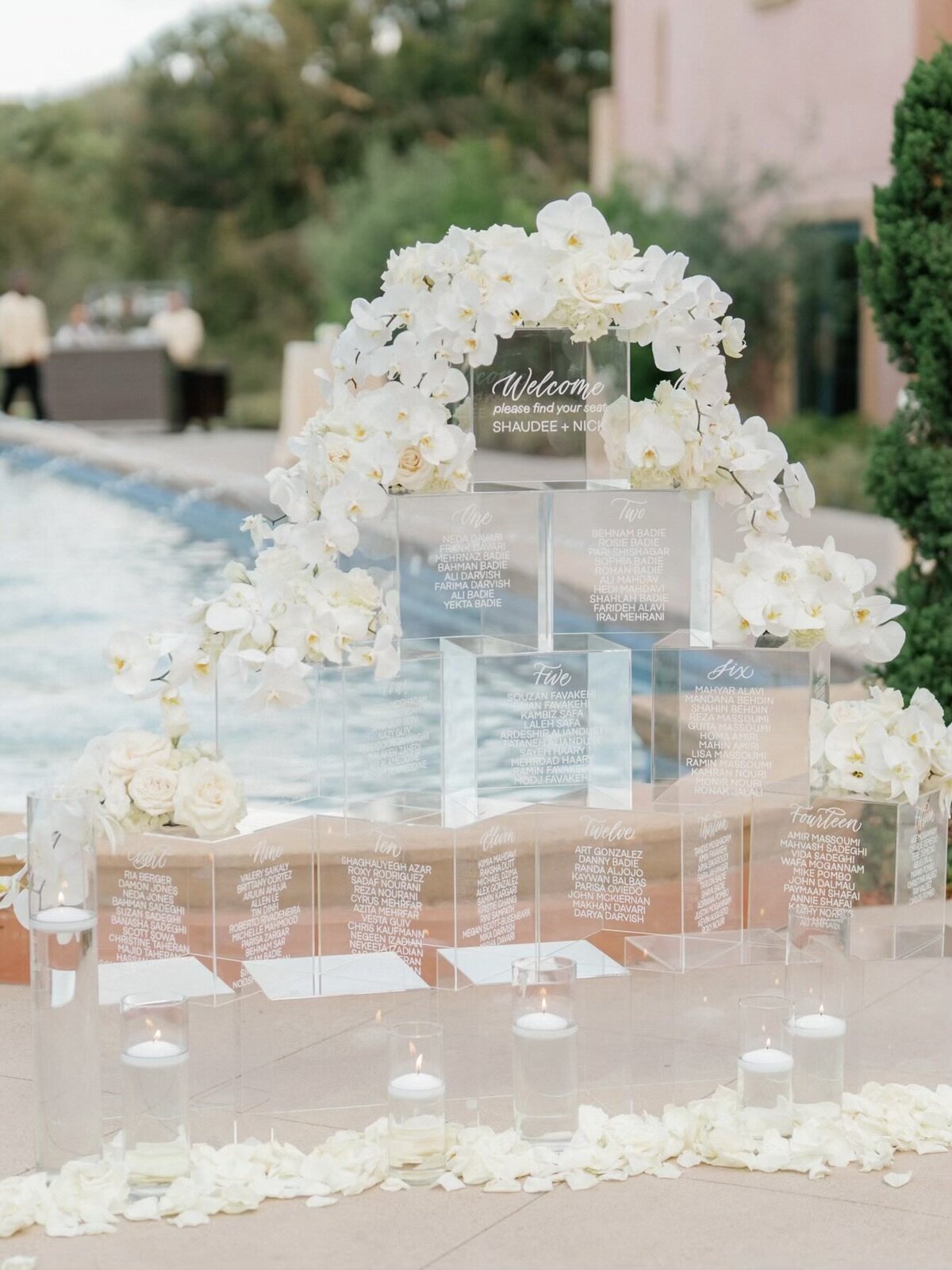 Clear acrylic boxes stacked to create a seating chart, decorated with white florals. Available for rent in the Bay Area