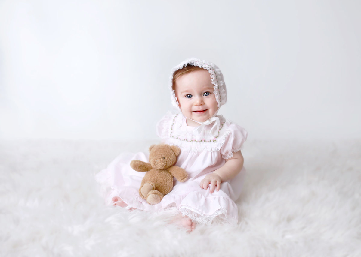 baby girl in light pink dress and bonnet