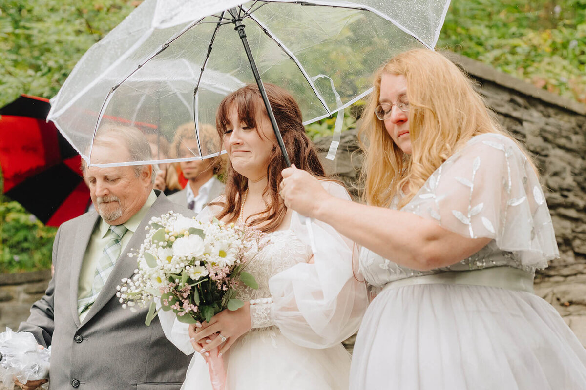 Bride walking down the aisle with umbrella held above her
