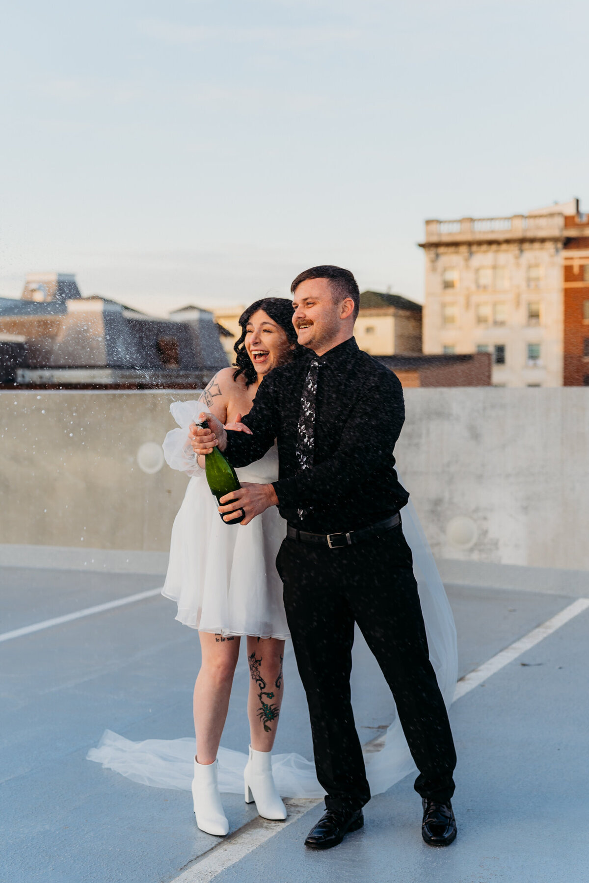 Couple popping champagne on rooftop during city elopement