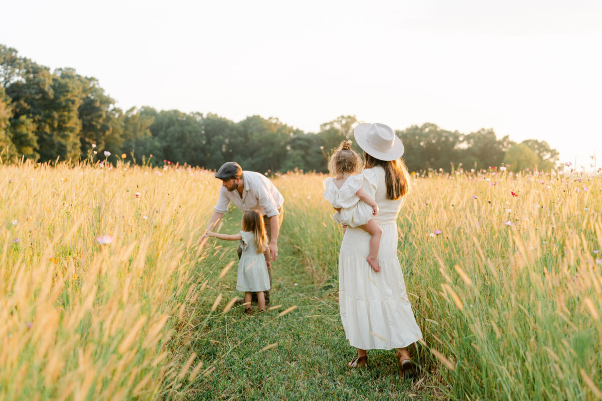 family walks with small toddlers through tall grass at sunset outside of Philadelphia