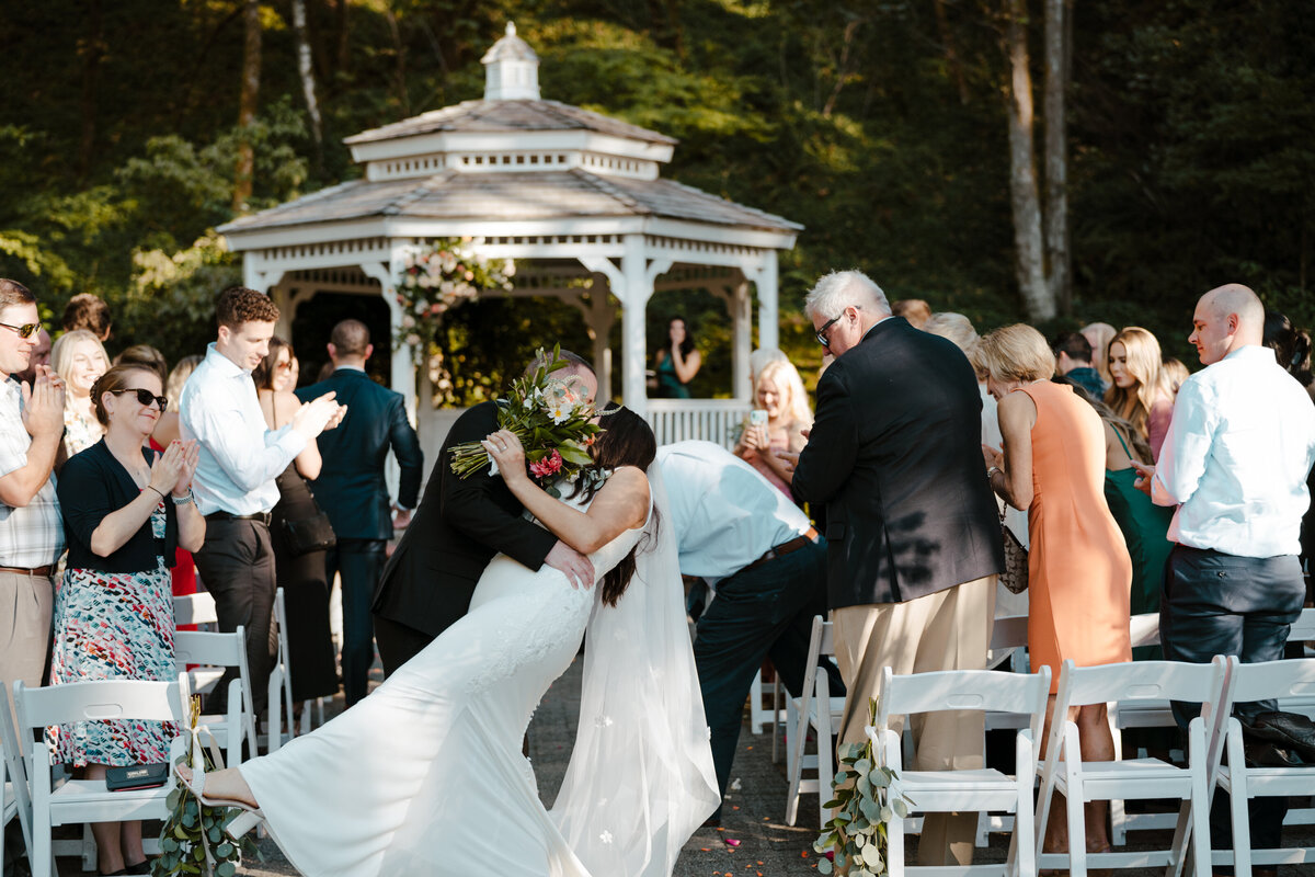 groom dipping and kissing bride after wedding ceremony
