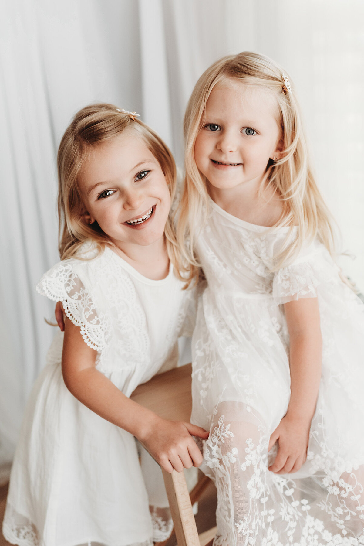 two girls in sweet white dresses looking at camera in photo session