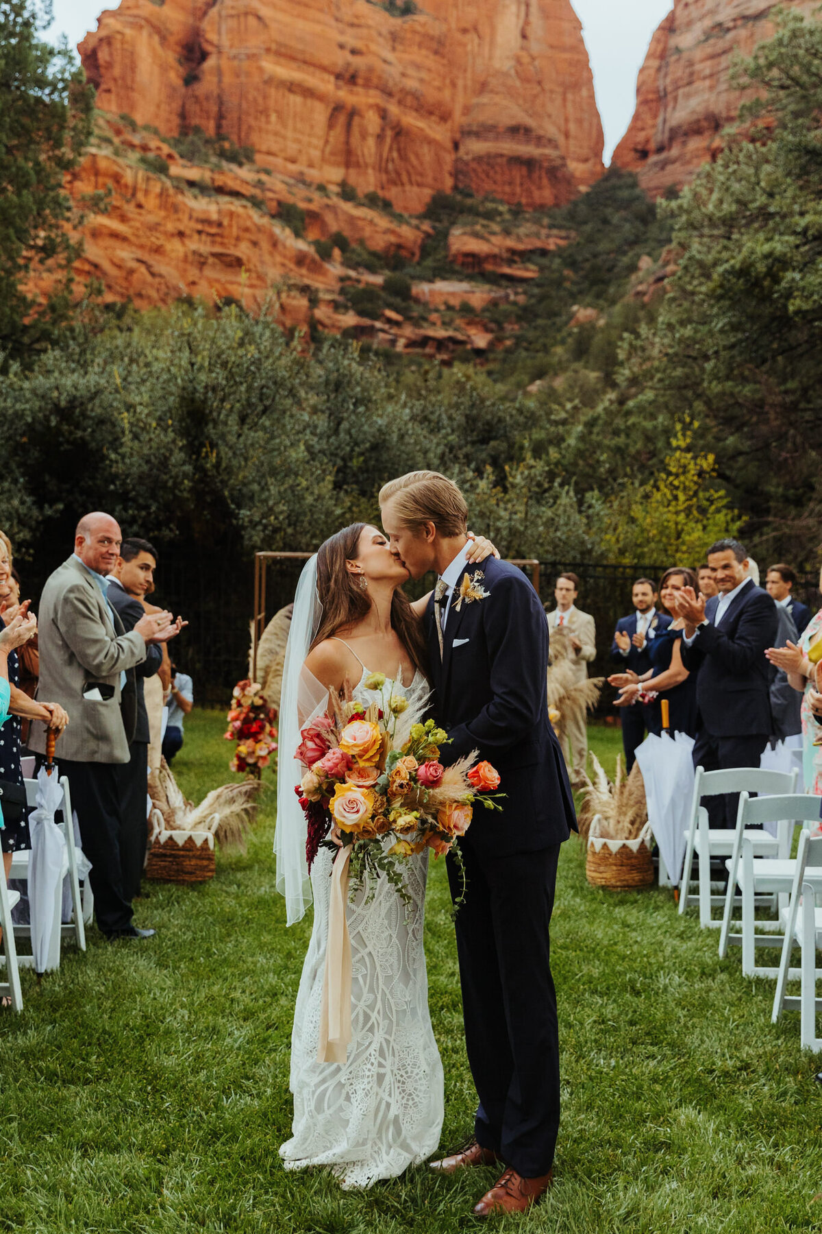 briude and groom kiss down the isle with red rocks behind them