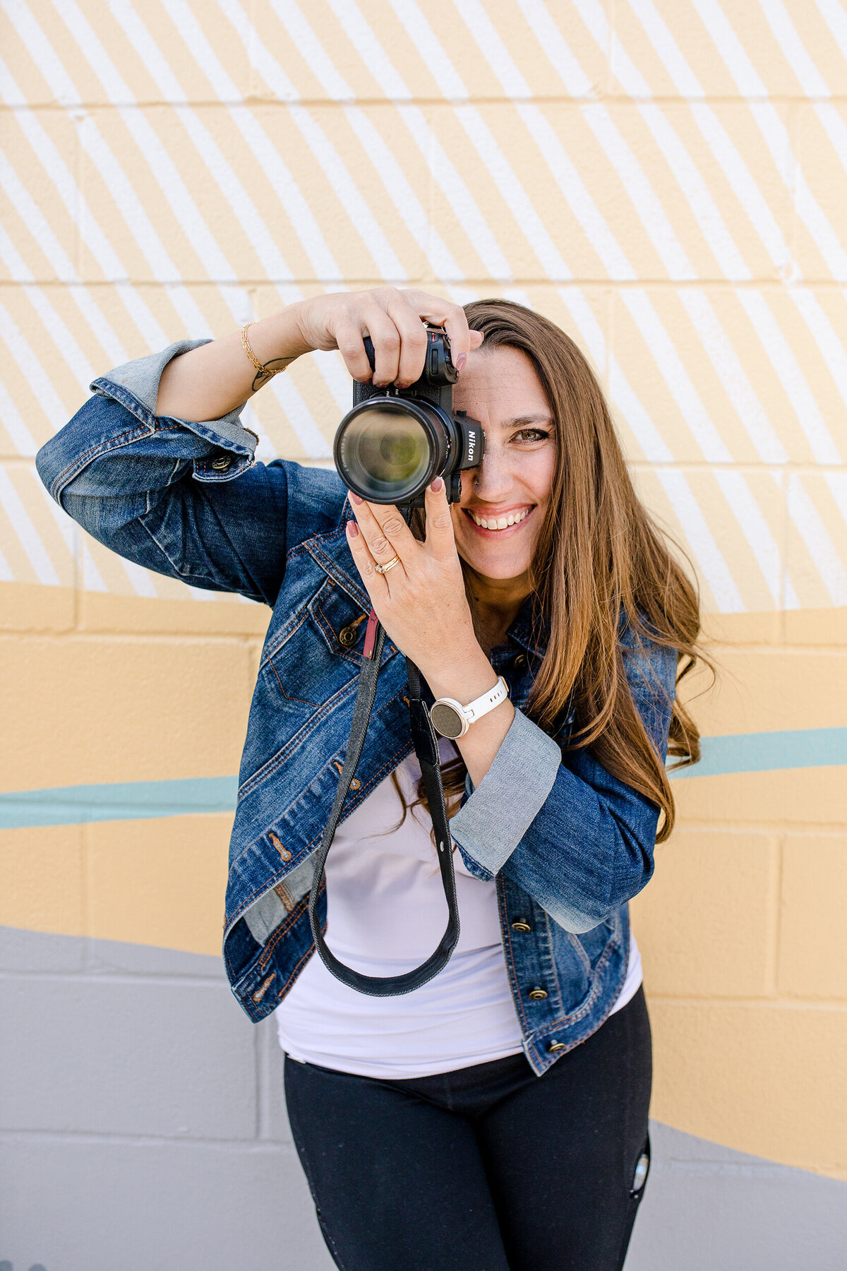 photography branding with headshot of a denver commercial photographers with her camera held up to her face as she smiles