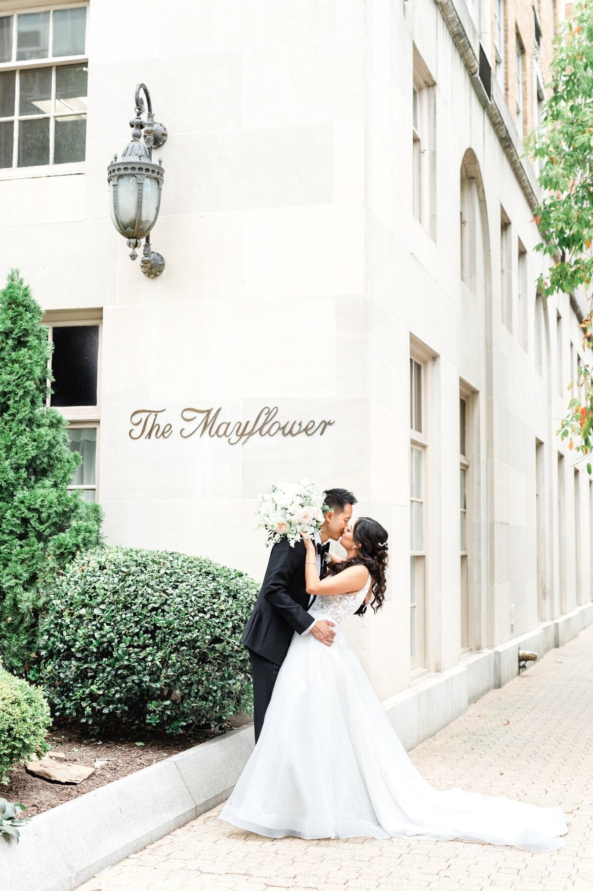 Groom kissing Bride outside of the Mayflower Hotel in Washington DC showing hotel sign