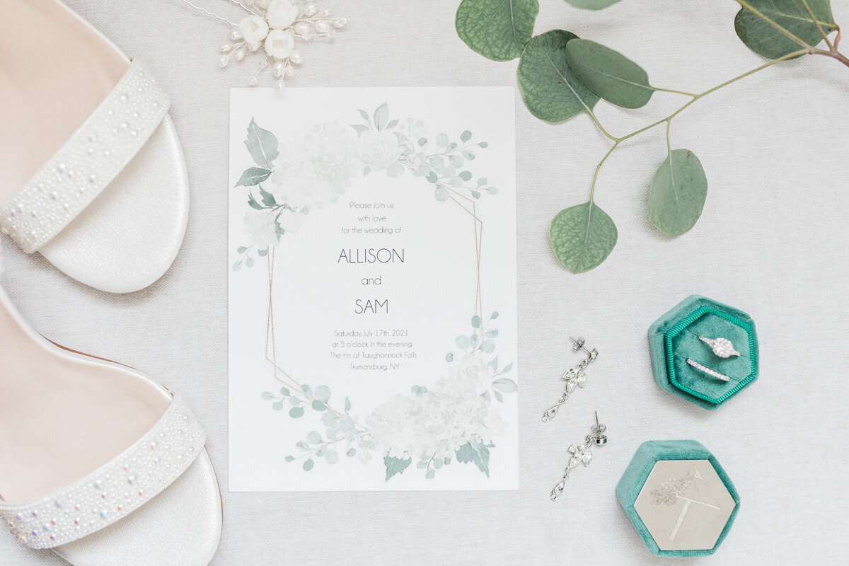 Bridal details with a wedding invitation and eucalyptus as an accent.