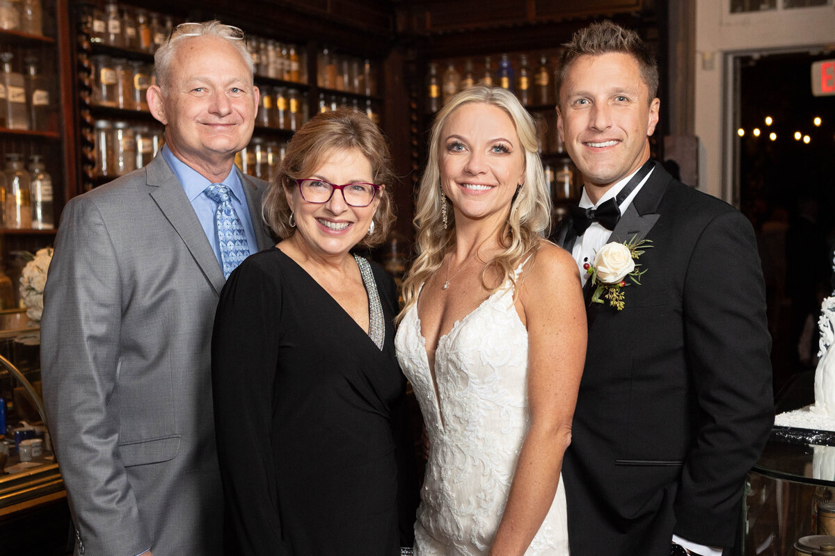 The couple takes a photo with a few guests at their wedding reception at the Pharmacy Museum in New Orleans, Louisiana.
