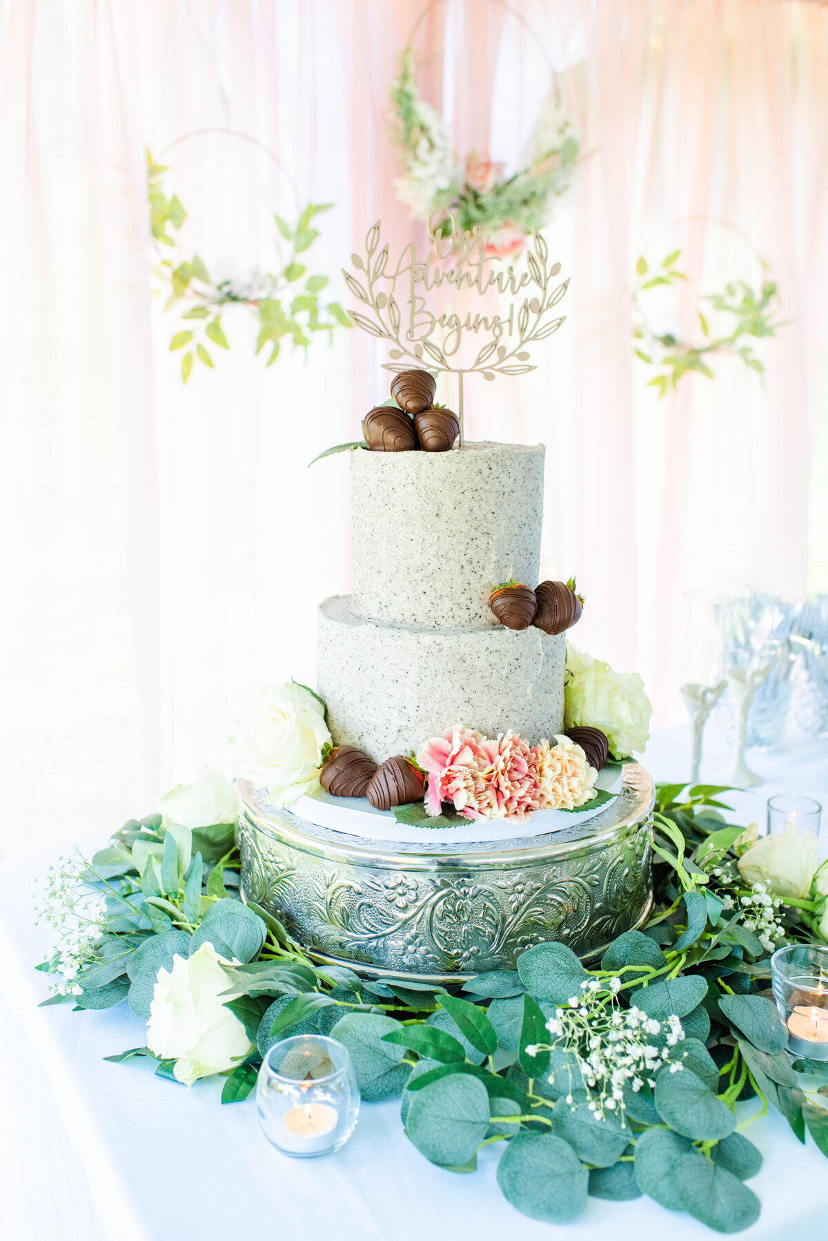white wedding cake decorated with flowers and chocolate covered strawberries