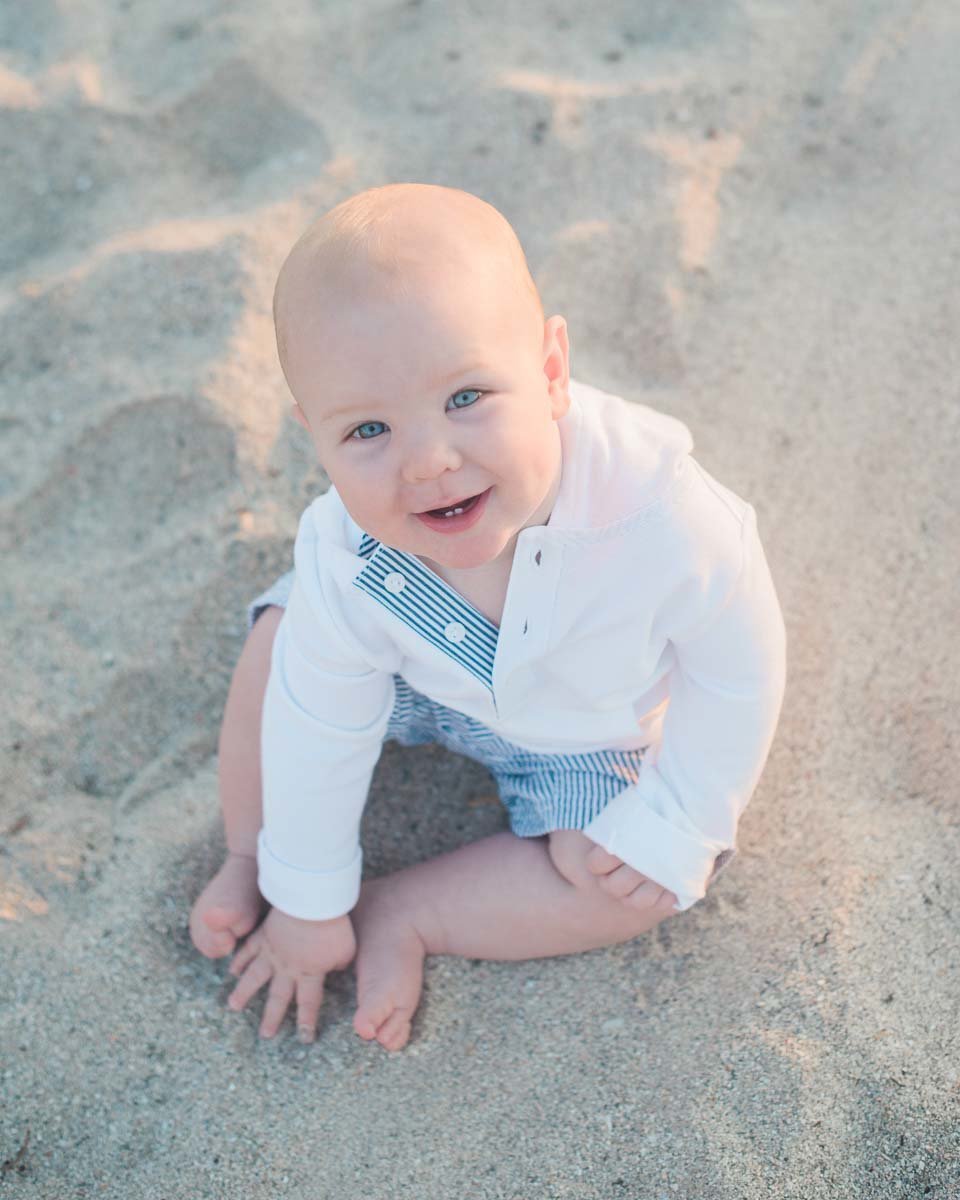 baby boy in white shirt sitting on beach