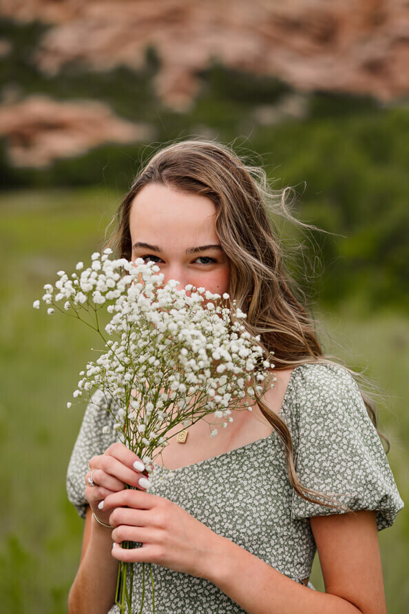 Girl hides her face behind a bouquet of baby's breath.