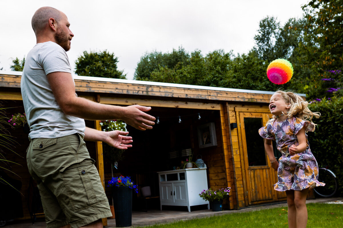 gezinsfoto thuis vader en dochter spelen met bal