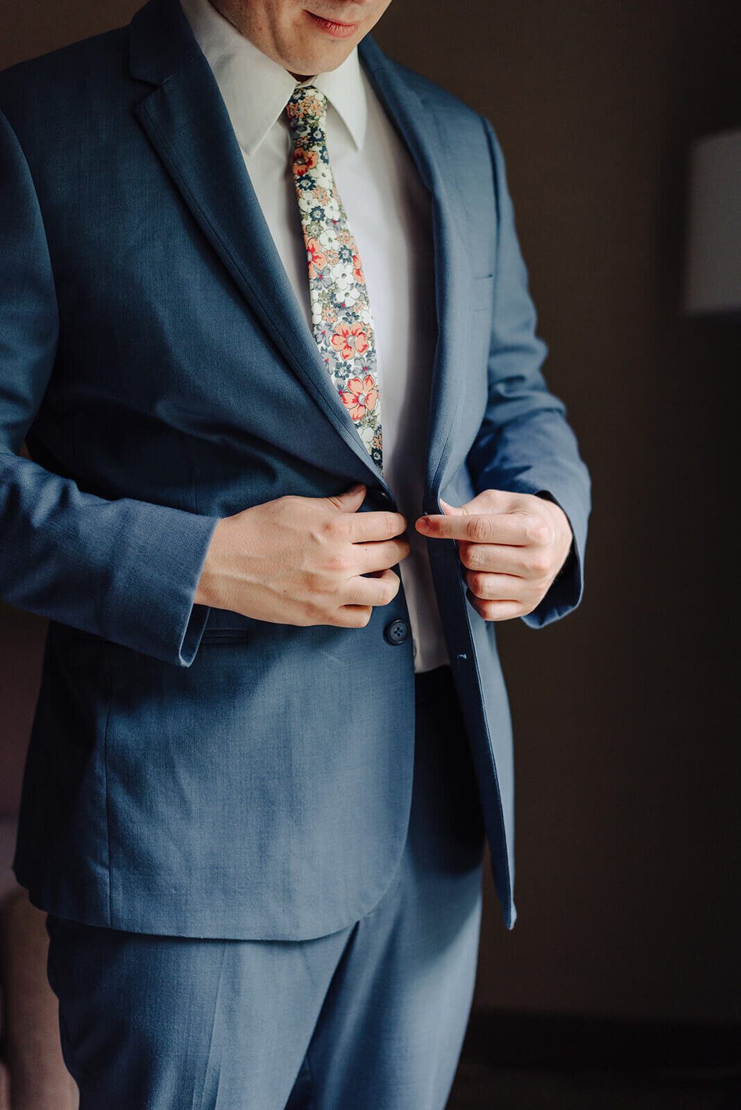 Groom buttoning up blue suit at Oswego wedding, NY