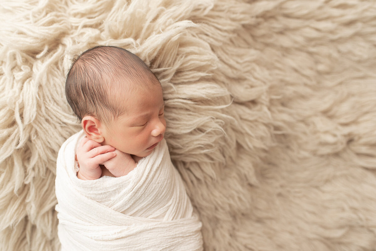 Side profile of newborn boy on tan rug, wrapped in white | Sharon Leger Photography | CT Newborn & Family Photographer | Canton, Connecticut