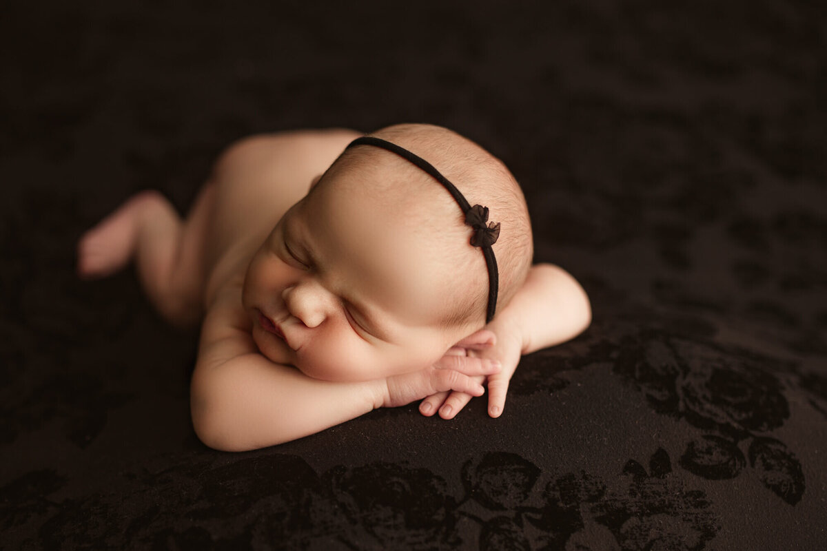 newborn girl posed on black blanket