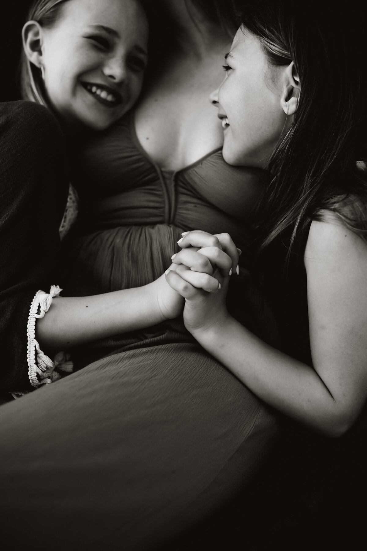 black and white portrait of 2 sisters holding hands and laughing