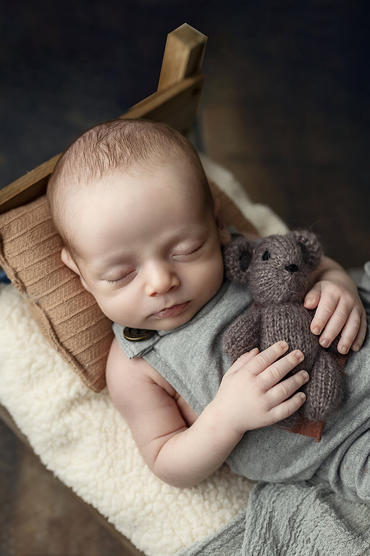 Baby boy holding a brown teddy bear.