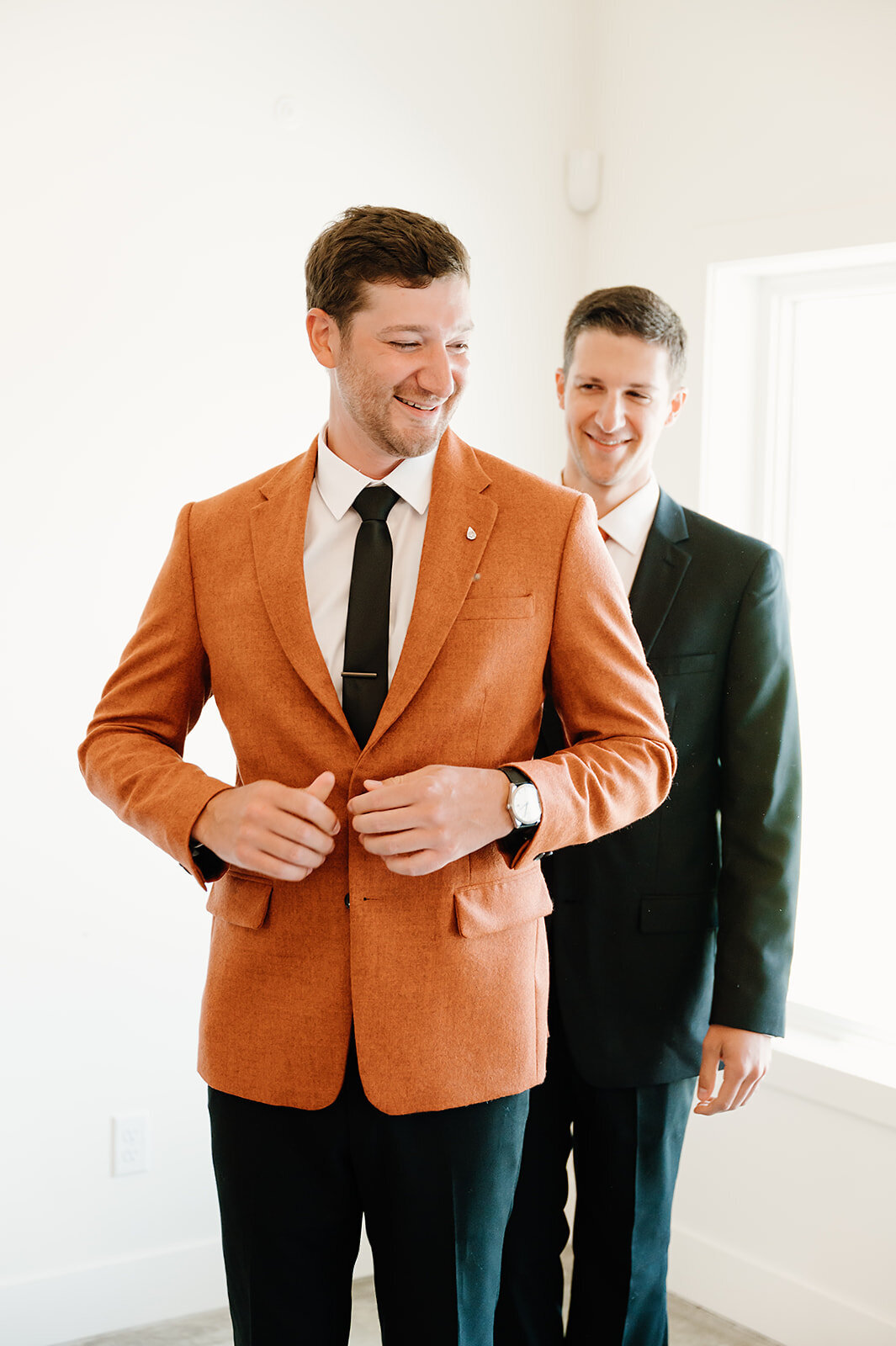 Groom in orange suit gets ready with brother
