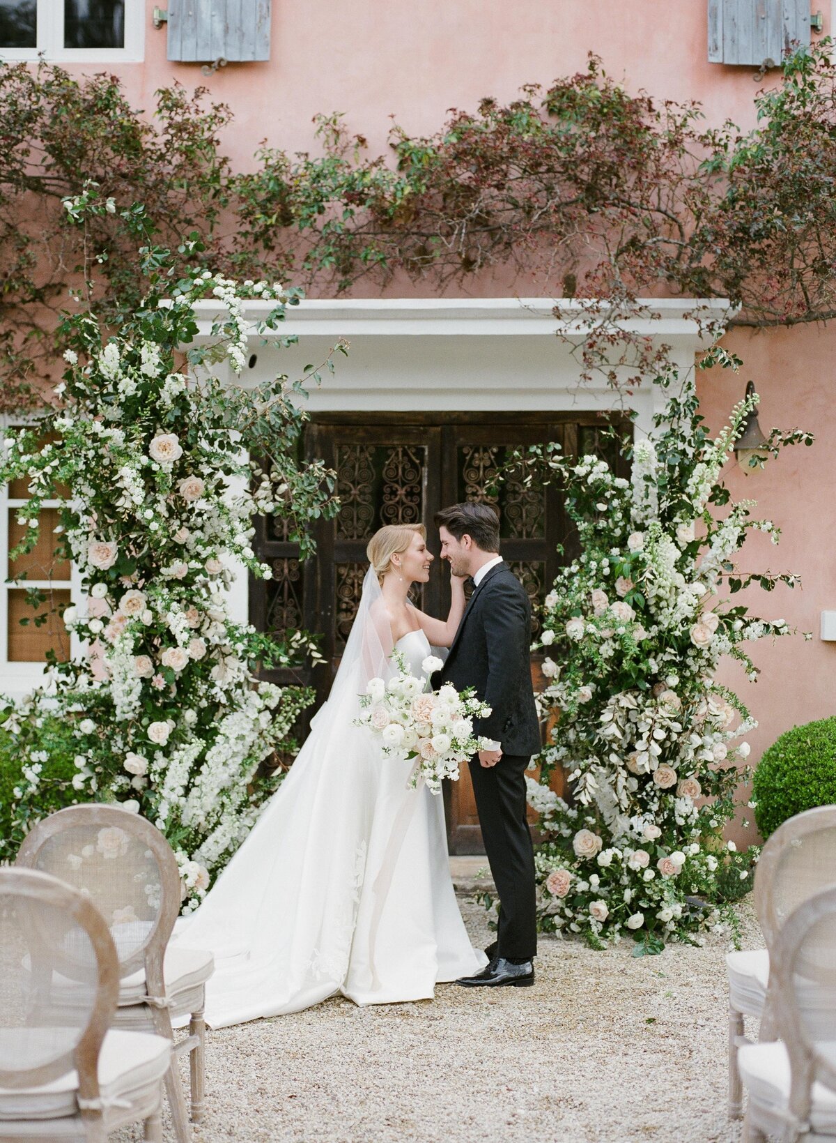 bride + groom with floral arbor