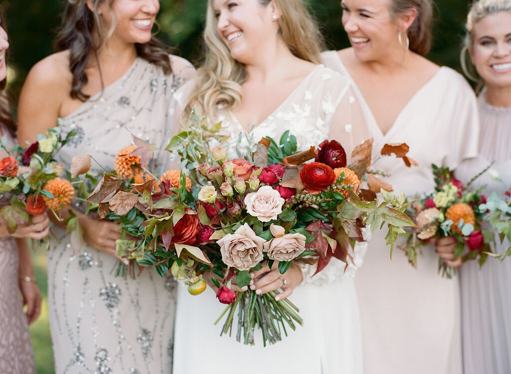 A whimsical bridal bouquet filled with burgundy, terra cotta, dusty rose and burnt orange florals. The bouquet features ranunculus, garden roses, dahlias, fruiting branches and autumn foliage. Designed by Rosemary and Finch in Nashville, TN.