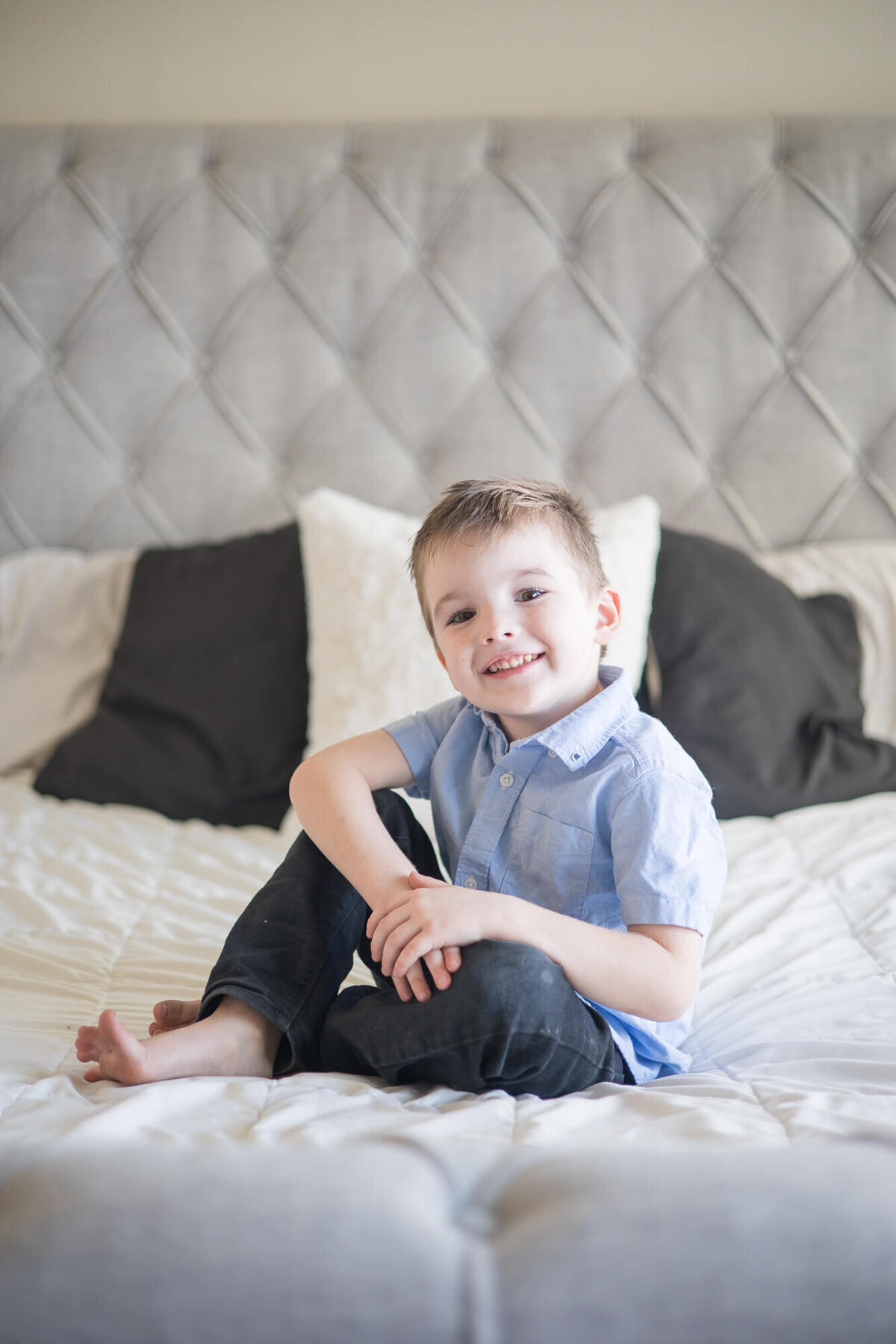 happy little boy on a white and gray bed