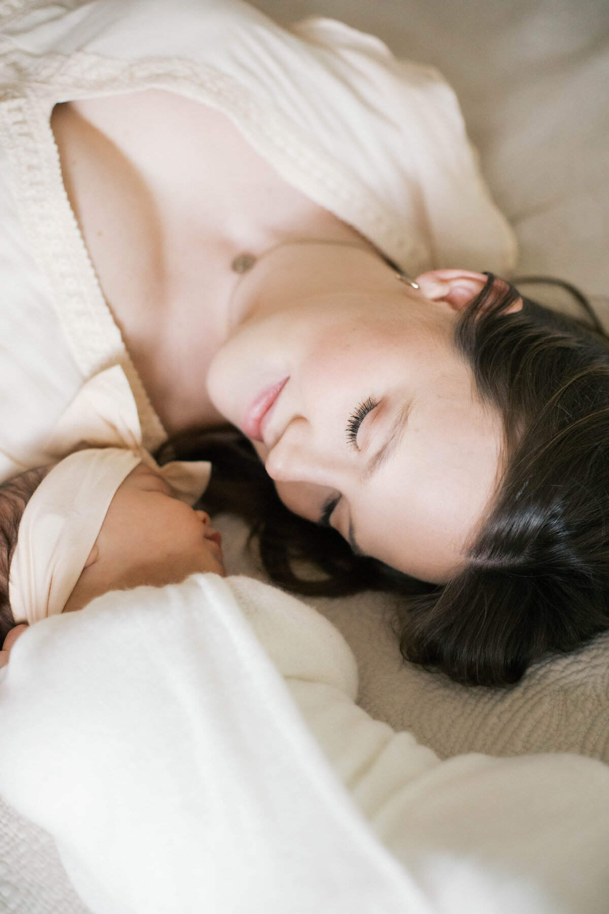 newborn portrait taken in home in Jacksonville with mom wearing a blush dress while laying down next to her newborn baby girl