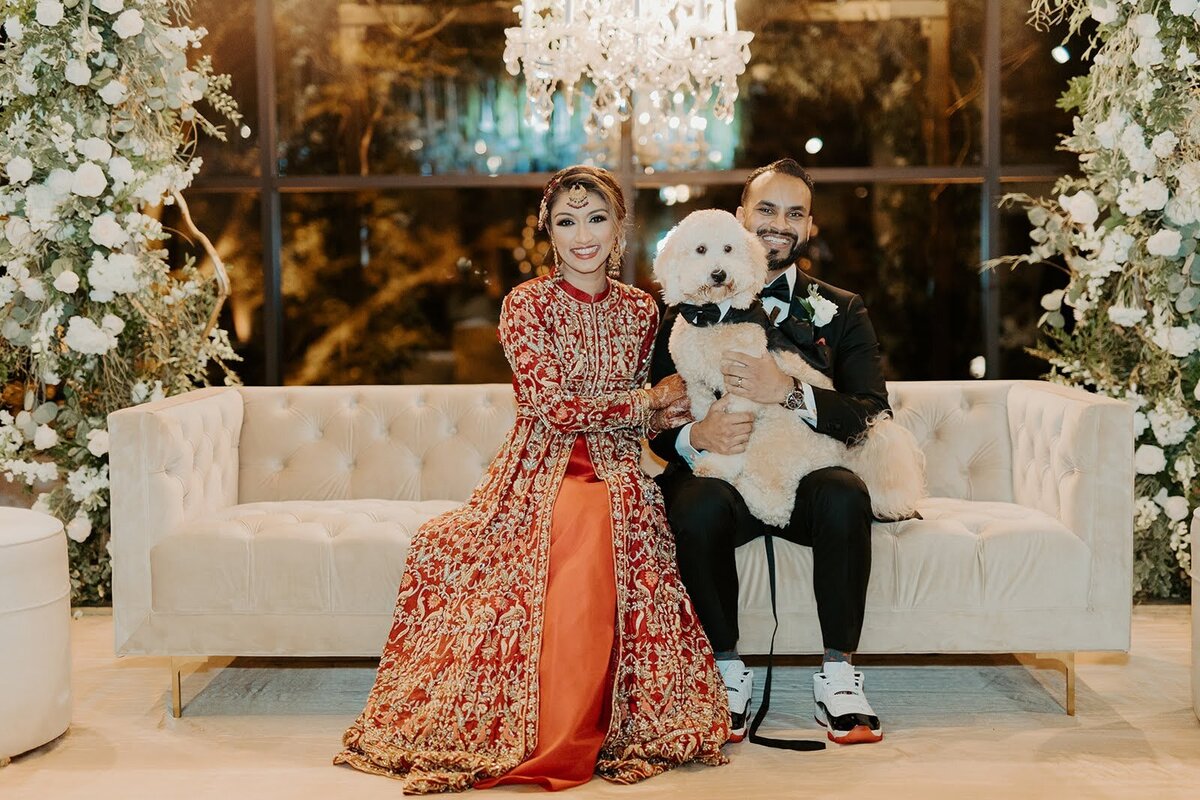 Bride and groom pose with their dressed up dog during their wedding reception at the Bowery House and Gardens.