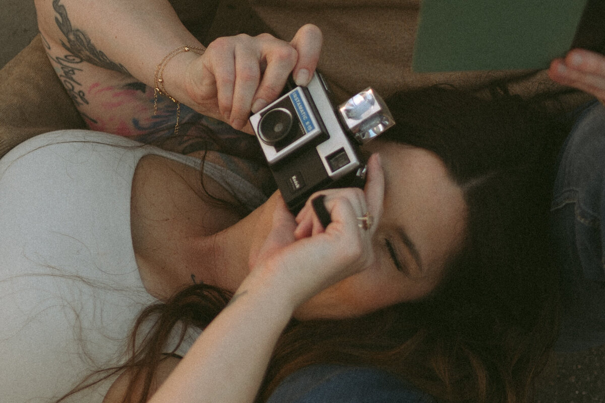 a woman taking a photo with a vintage film camera.