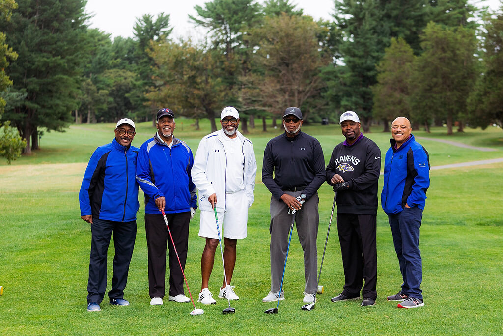 Six people pose with golf equipment.